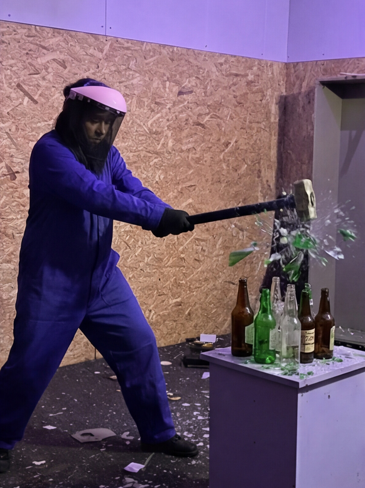 Persona destrozando botellas de cristal con una maza en la Rage Room de Break&Joy