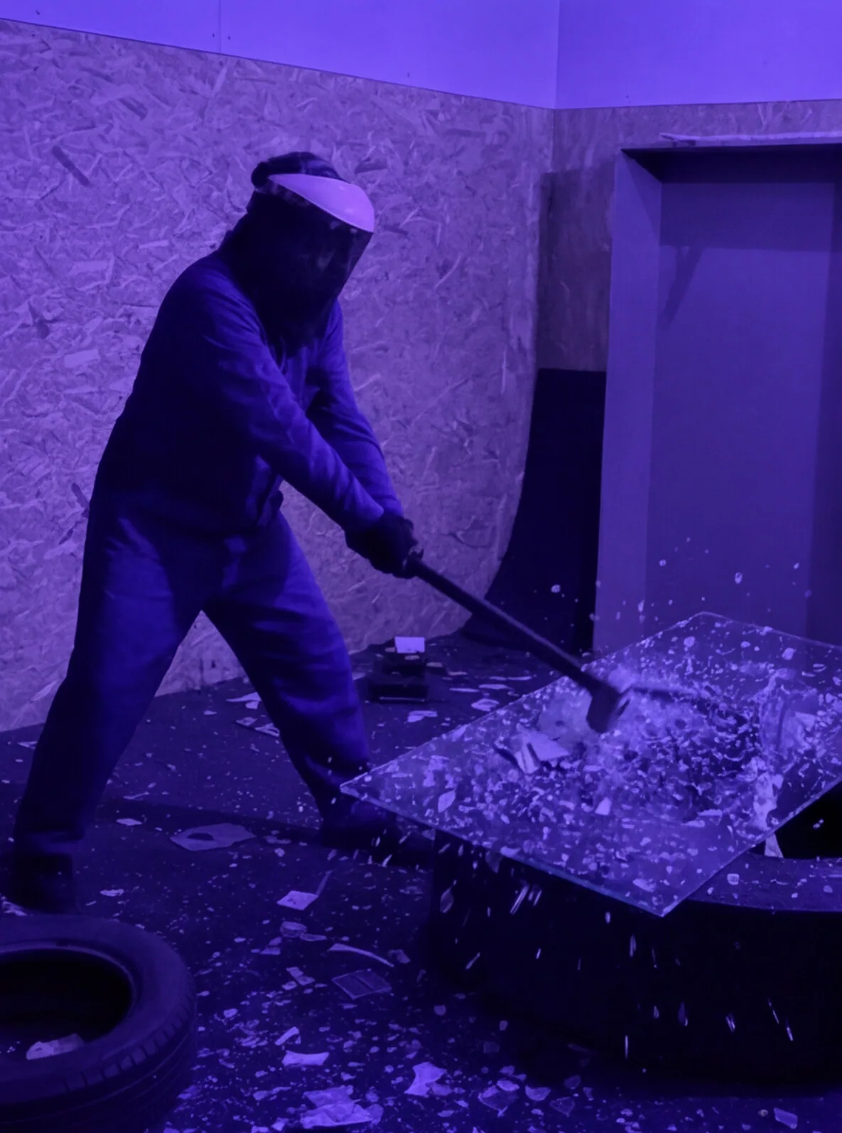 Persona destrozando cristales sobre una mesa en la Rage Room de Break&Joy Granada