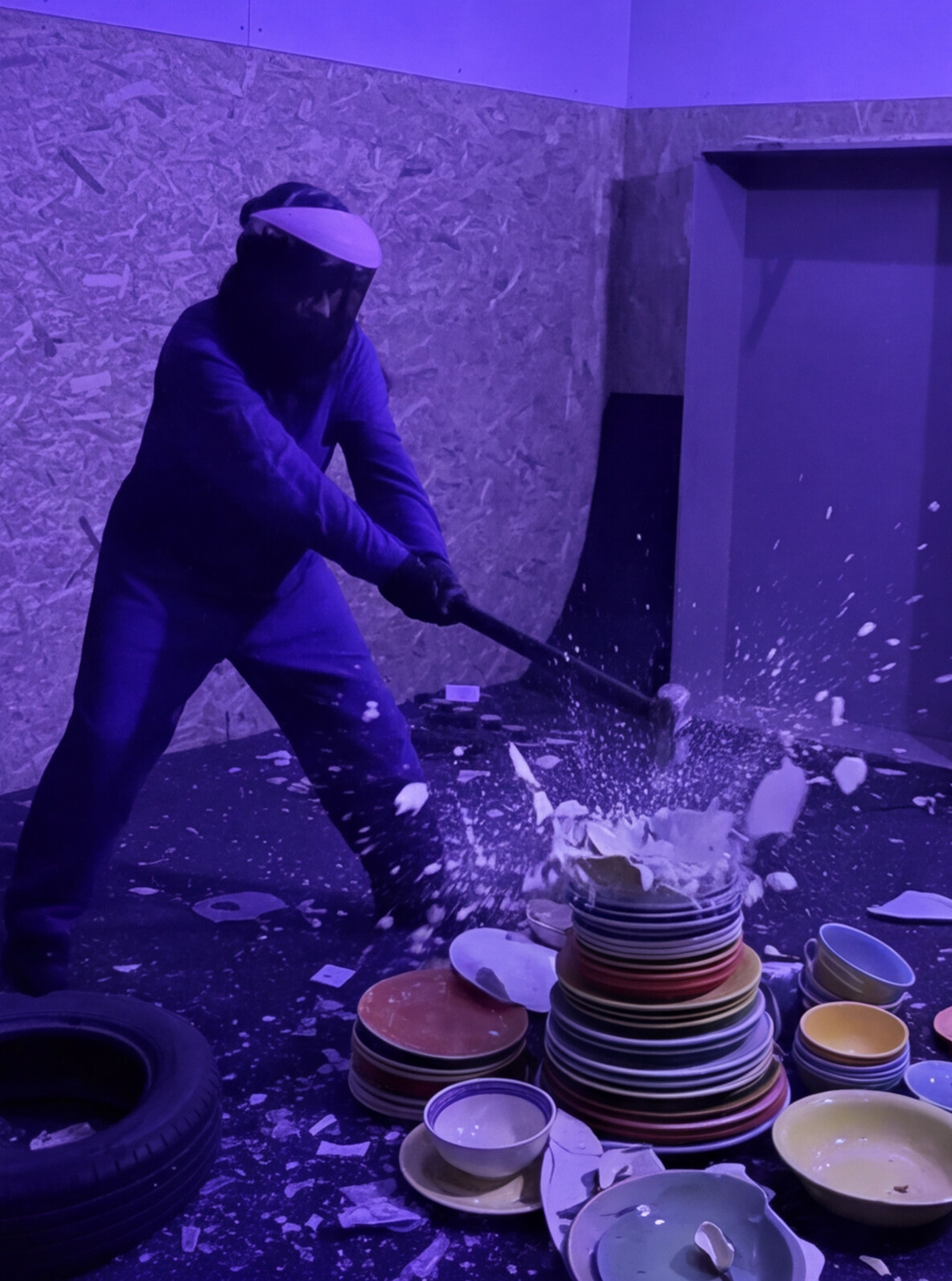 Persona rompiendo una pila de platos de colores con una maza en la Rage Room de Break&Joy