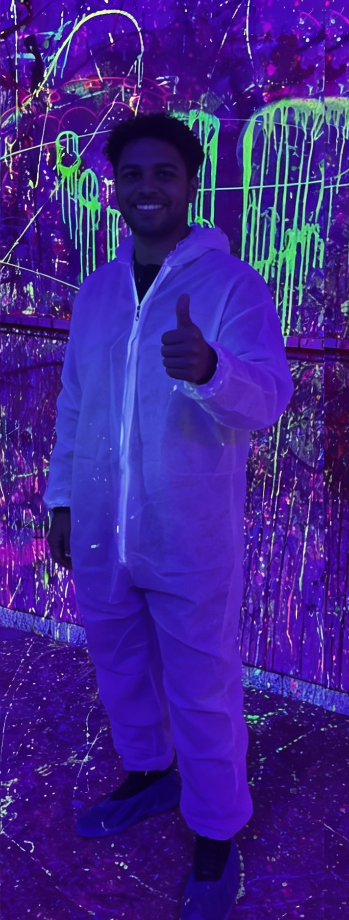 Persona con mono blanco posando feliz en la Splatter Room de Break&Joy bajo luz UV