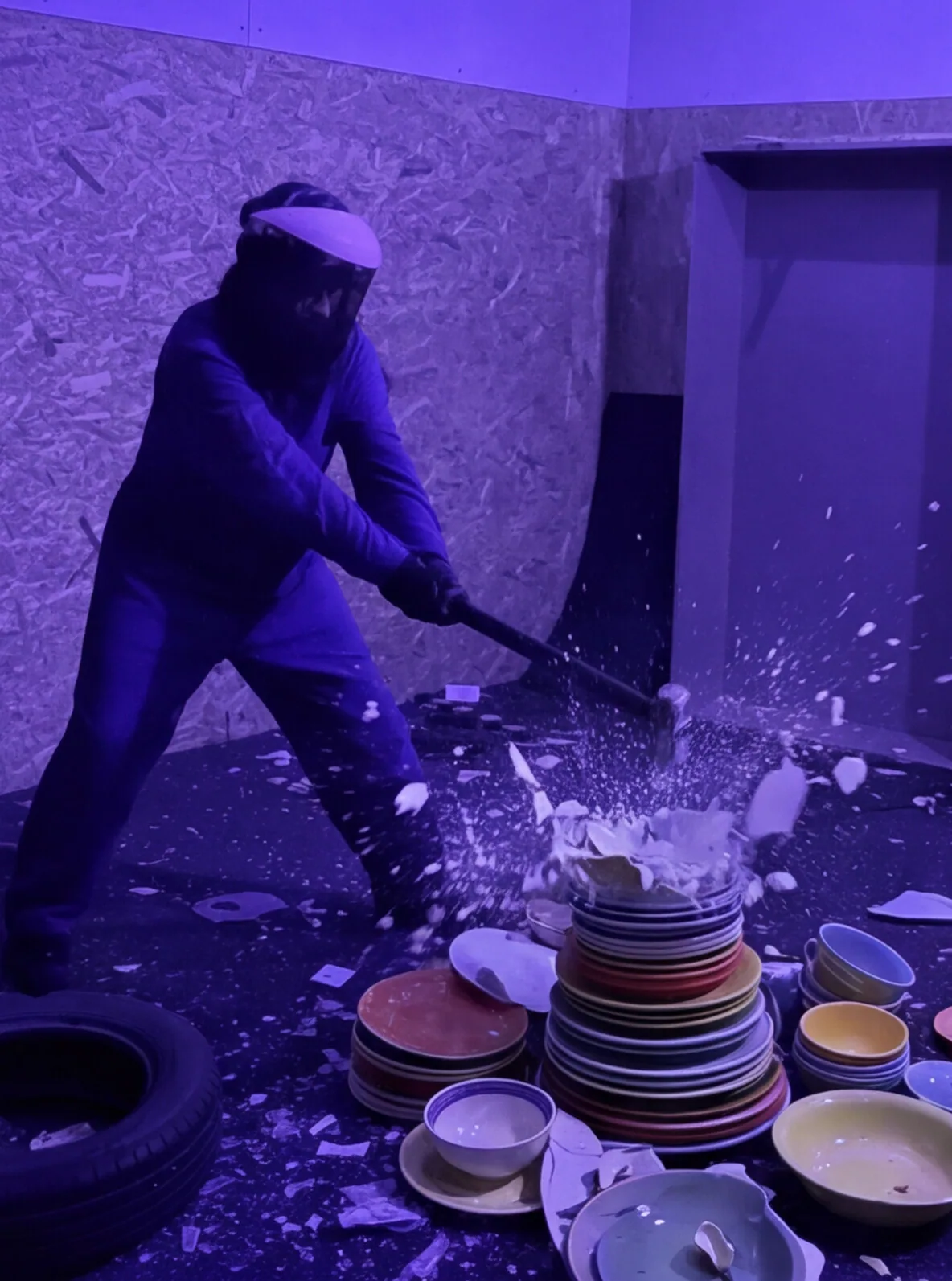 Persona rompiendo una pila de platos de colores con una maza en la Rage Room de Break&Joy