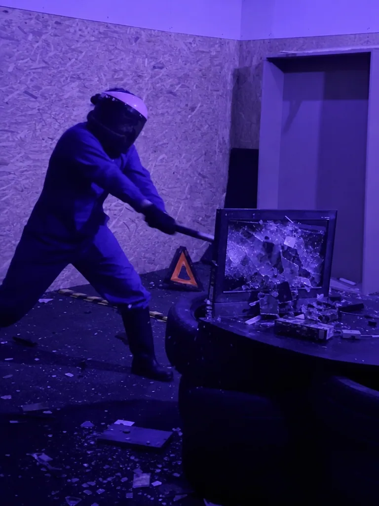 Persona destrozando un monitor con una maza en la Rage Room de Break&Joy