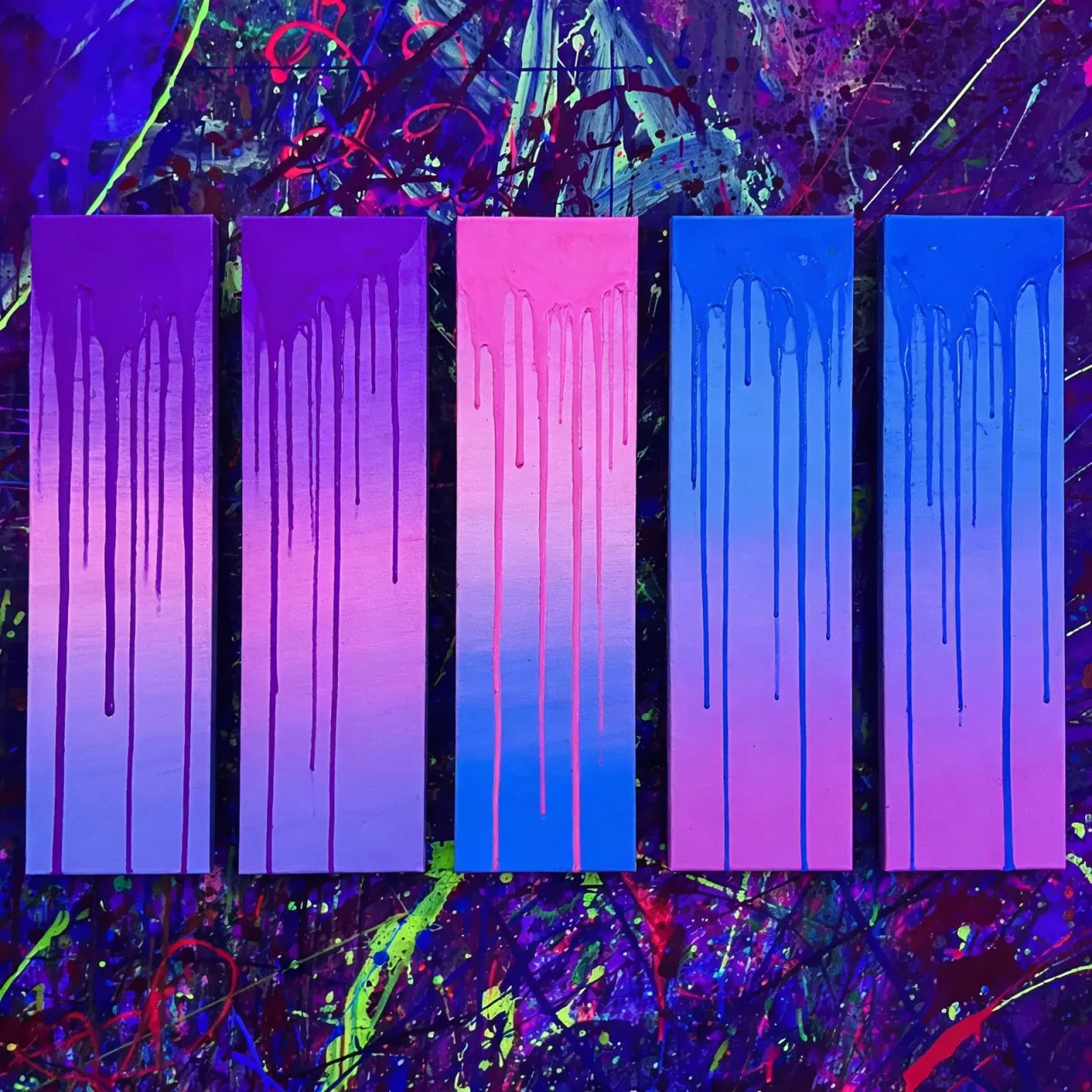 Cinco lienzos con drips de pintura en degradado rosa, azul y morado bajo luz UV